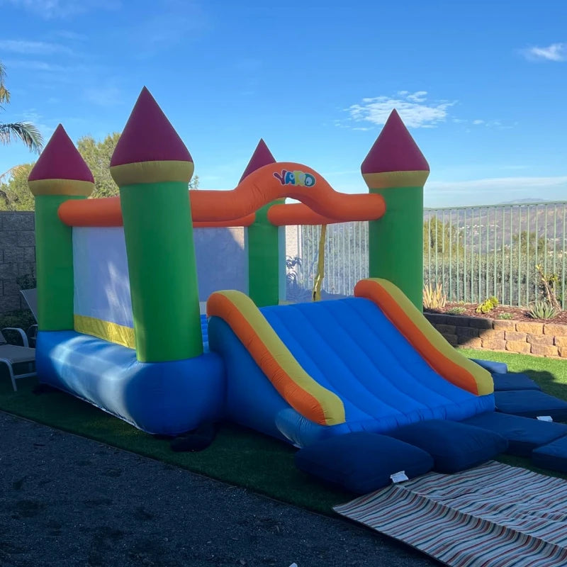 Chèteau gonflable coloré avec toboggan déployé en jardin